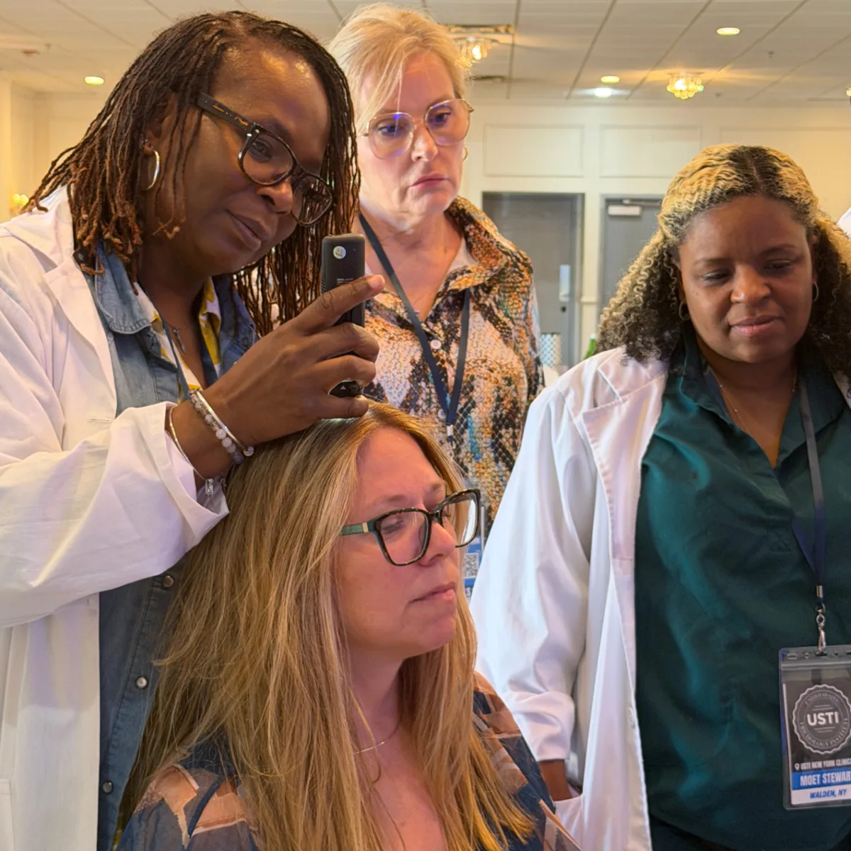 A USTI trichologist scoping a client's scalp while classmates watch