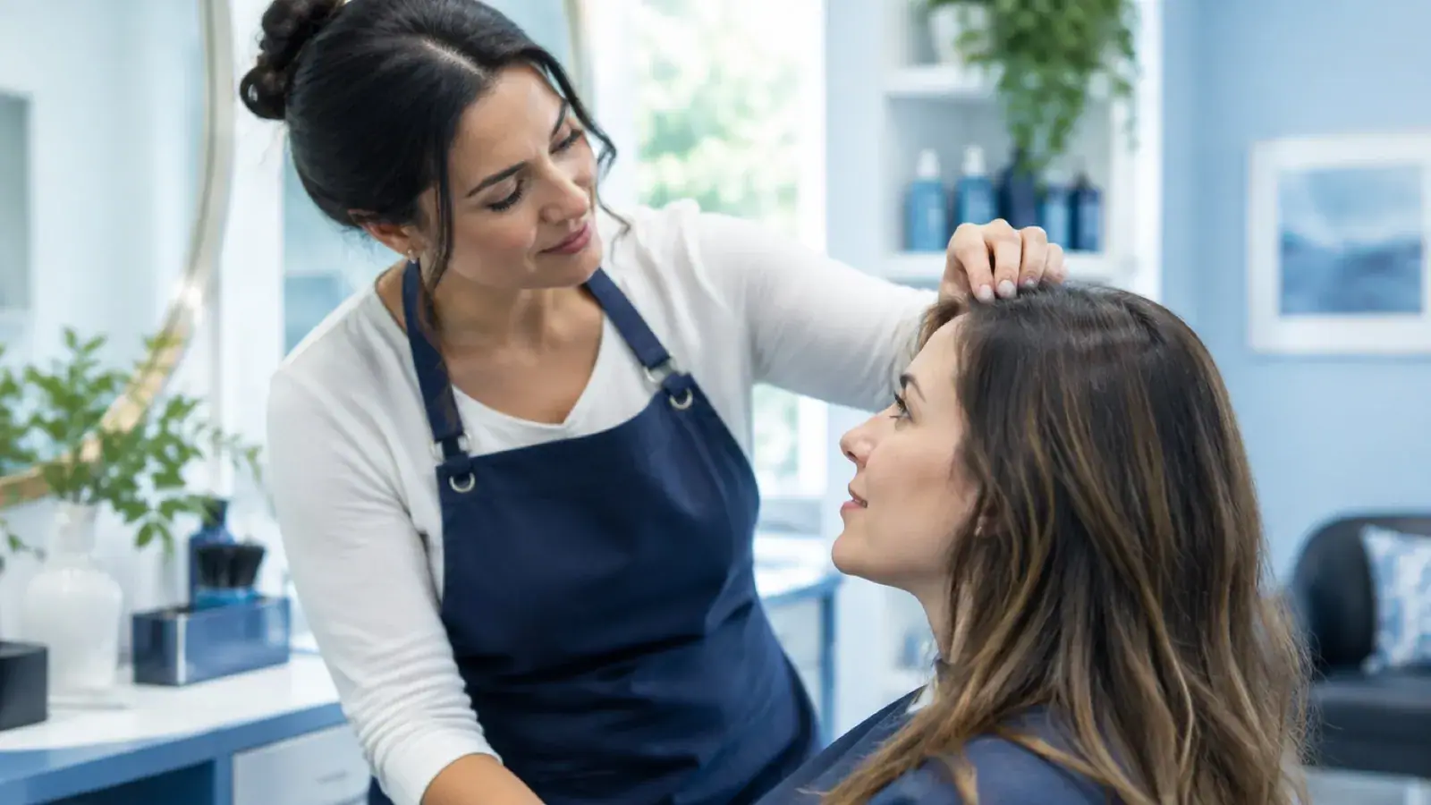 Hairstylist looking at a client's scalp near the hairline during a consultation